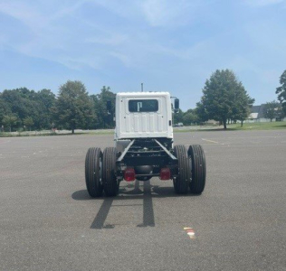 Cab chassis truck rear view showing dual rear axles and Hino L6 chassis with empty cab, white cabin, in a parking lot.