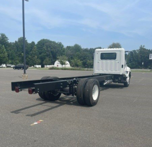 Chassis cab truck rear view showing bare frame and dual rear wheels, white cab, empty truck bed area, rear lights visible.