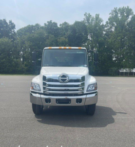 Front view of a white Hino cab chassis truck with large chrome grille, round headlights, bumper, and amber clearance lights on roof.