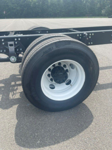 Wheel and chassis frame of a Hino truck showing dual rear wheels and black undercarriage components.