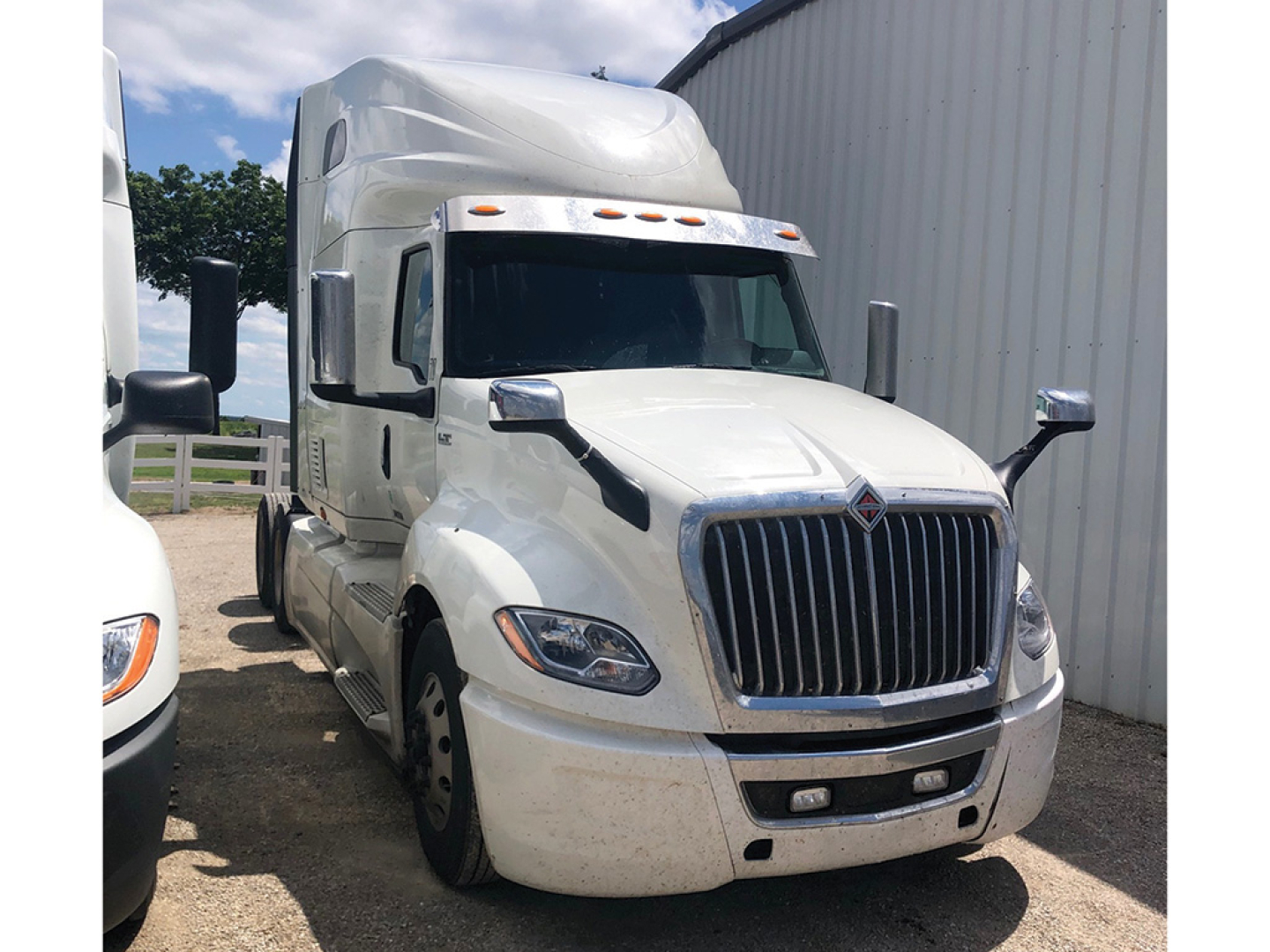 Truck cab exterior showing front grille and headlights of a white 2022 International LT625 conventional sleeper (tractor) from driver's side angle.
