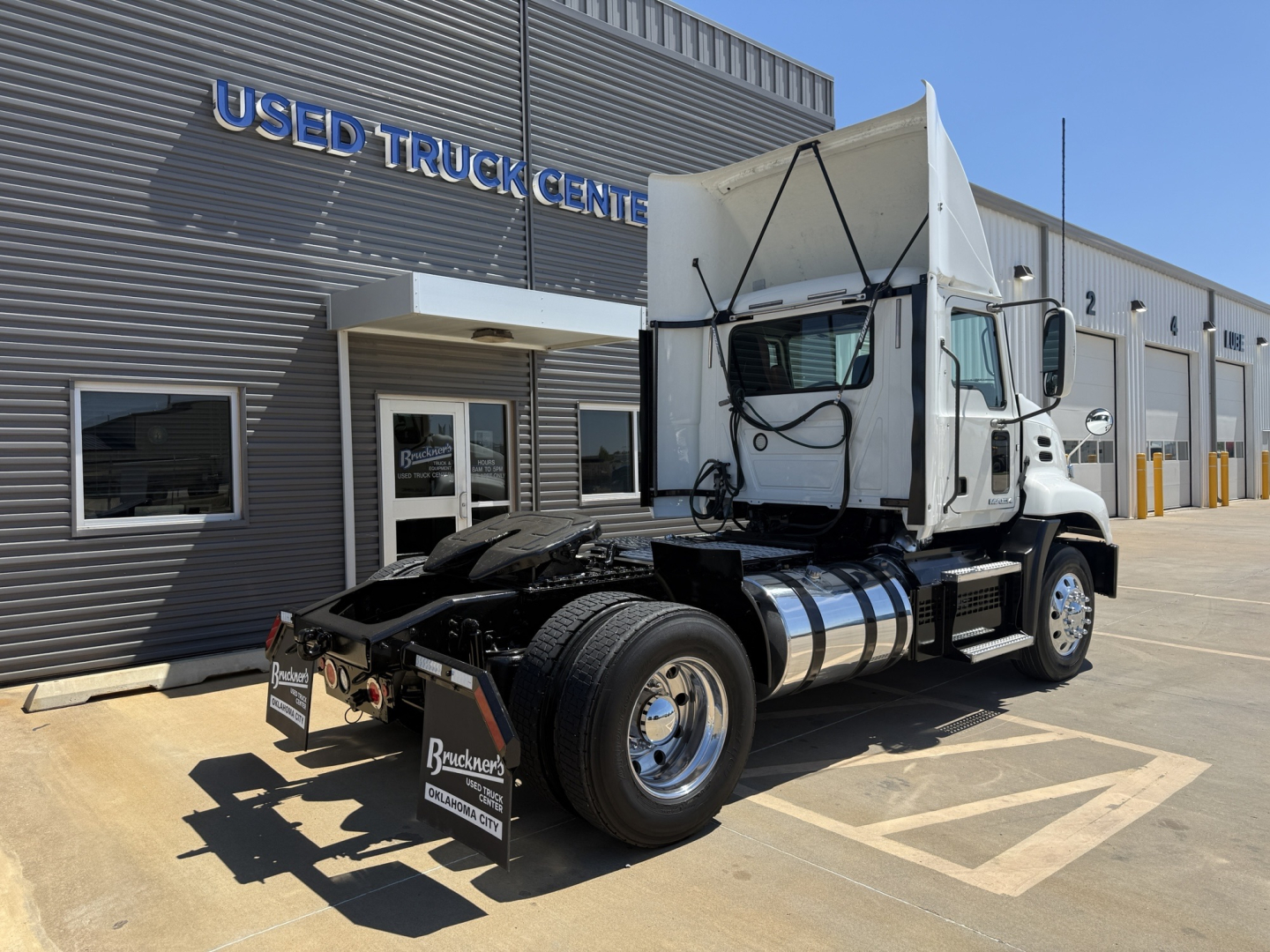2018 Mack CXU612 conventional daycab tractor in front ofUsed Truck Center building showing side and rear view
