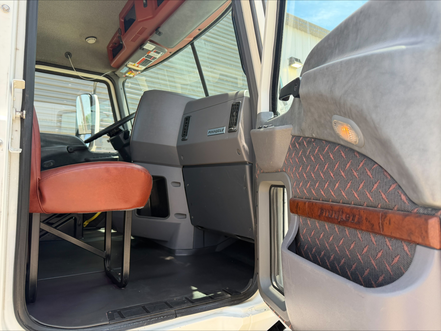 Cab interior of 2018 Mack CXU612 truck showing driver seat, dashboard, and entry area seen from open door.