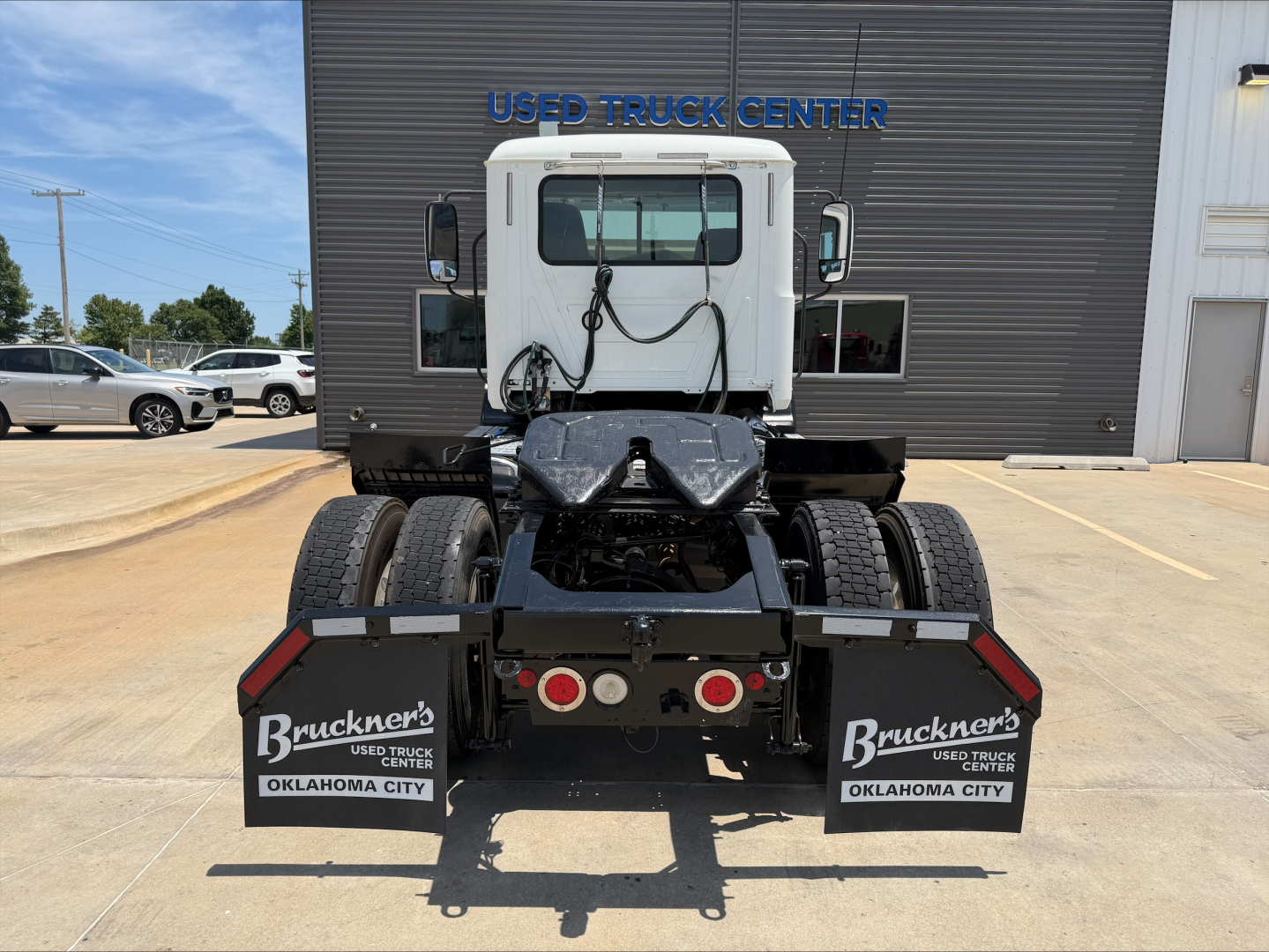 Mack CXU612 truck chassis rear view showing dual rear axles and mud flaps with Bruckner’s Oklahoma City branding.