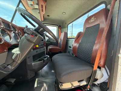 Cab interior of a 2018 Mack CXU612 daycab showing steering wheel, dashboard, and two front seats with upholstery; windshield and side window visible.