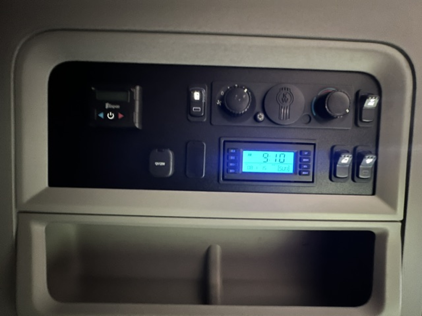 Kenworth T680 dash panel showing control switches and blue digital display in cabin