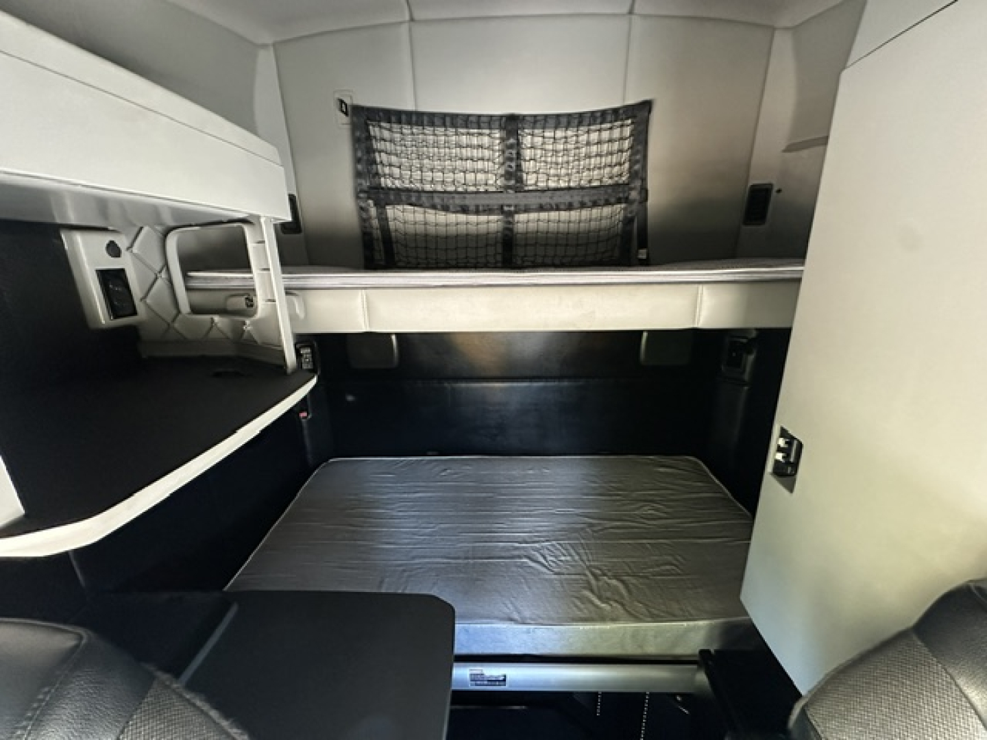 Kenworth T680 sleeper cab interior with bunk bed and storage shelves visible.