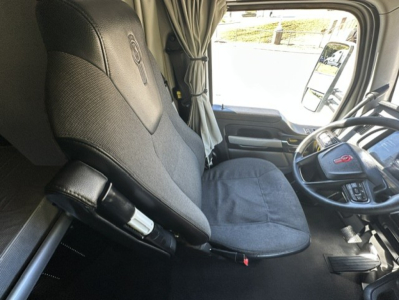 Kenworth T680 cab interior showing driver seat and steering wheel with gray upholstery and control levers.