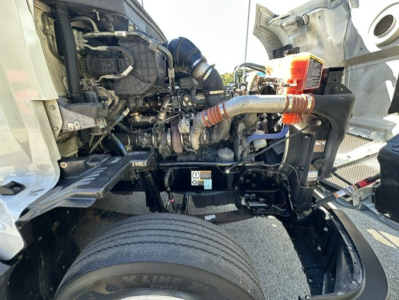 Kenworth T680 engine bay showing front suspension, air intake, hoses, and radiator area.