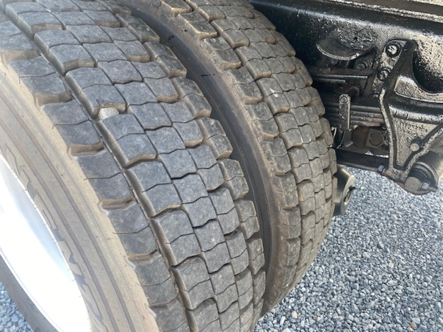 Truck dual rear wheels showing heavy tread tires and rear suspension components in the wheel well of a 2007 International 7400 dump truck.