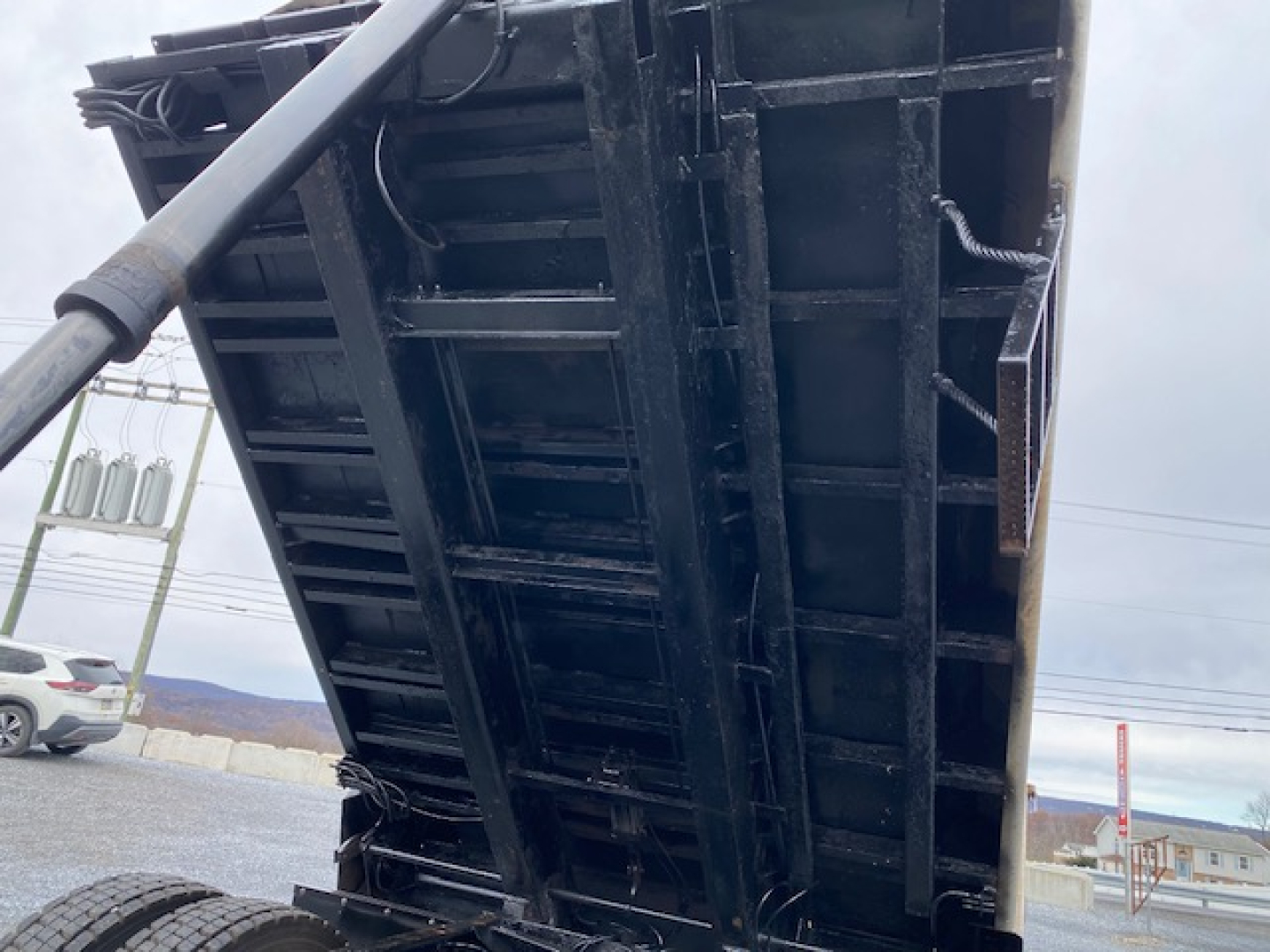 Dump bed of a 2007 International 7400 truck in vertical orientation showing black steel bed with hydraulic cylinder and support beams.