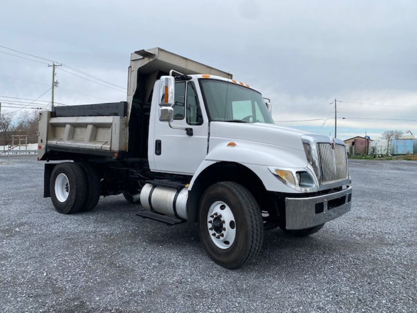 Dump truck showing cab and dump bed, International branding, white cab with black chassis and dumping bed, front grille with chrome accents, side mirrors, and wheel wells.