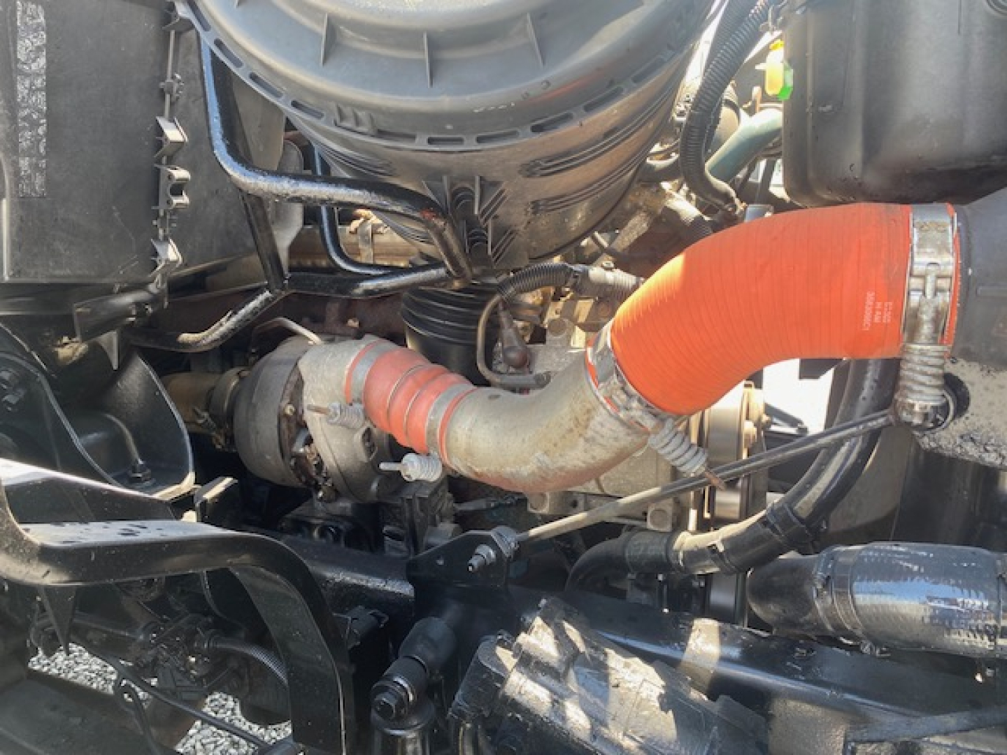Engine bay of a 2007 International 7400 dump truck showing orange intercooler hose, air intake, and surrounding components.
