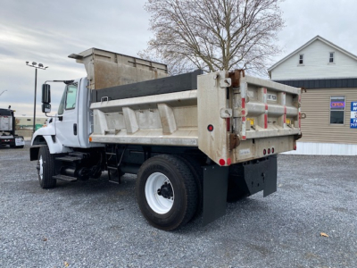 Dump truck with white cab and open-top dump bed, rear view showing taillights and hydraulic mechanism, text on rear panels and license area; appears to be a 2007 International 7400 dump truck.