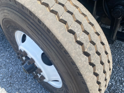 Tire and wheel of a 2007 International 7400 dump truck showing heavy tread and white steel rim.