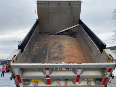 Dump truck bed of a 2007 International 7400 with open tailgate showing cargo bed and hydraulic mechanism, metal surface with wear.