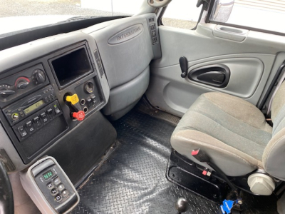 Cab interior of a 2007 International 7400 dump truck showing driver and passenger seats, dashboard with controls, and textured floor mat.