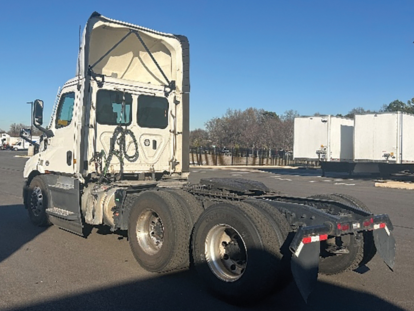 Freightliner Cascadia 116 daycab tractor chassis showing rear 3-axle drive configuration and raised cab with VIN/stocker details in image.