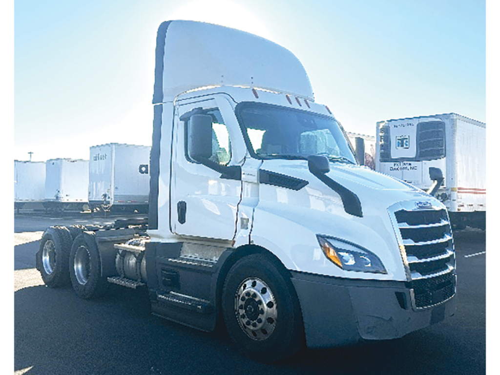 Conventional daycab truck in a parking lot showing Freightliner Cascadia 116 cab and front wheel area.