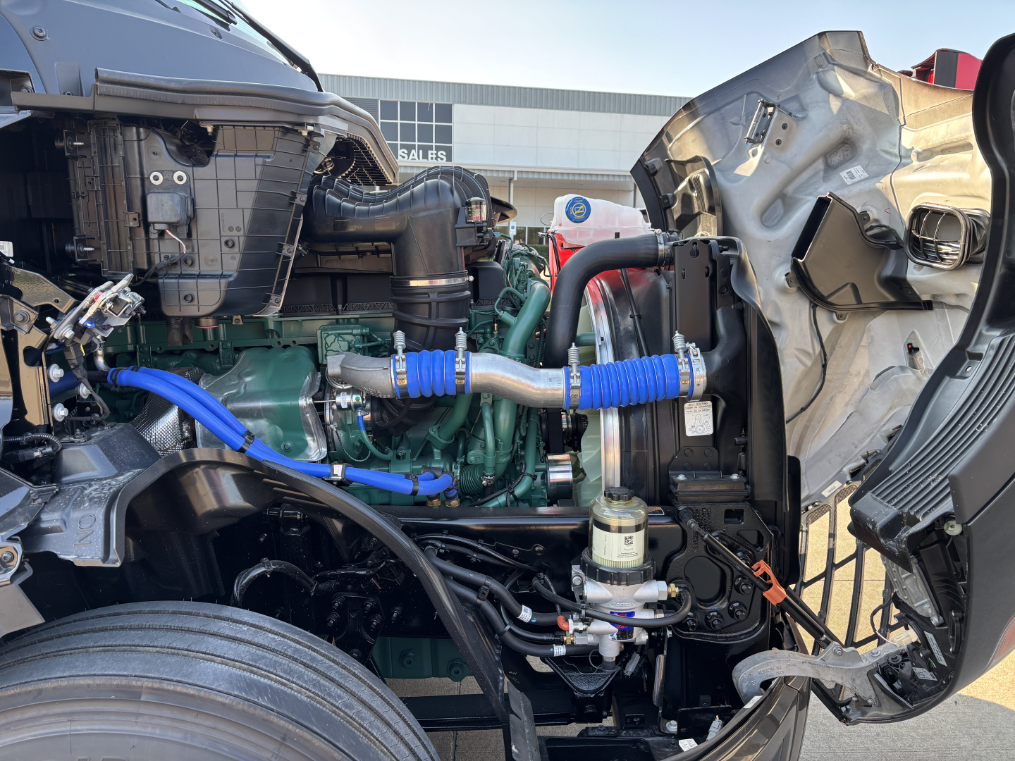 Volvo VNL64T860 engine bay view with green engine, blue hoses, intercooler piping, and exposed components.