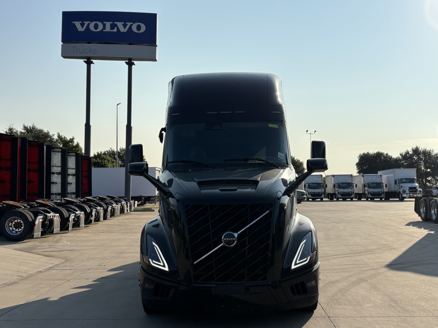 Volvo VNL64T860 truck in a dealership lot, front view with distinctive LED daytime running lights and Volvo emblem on grille.
