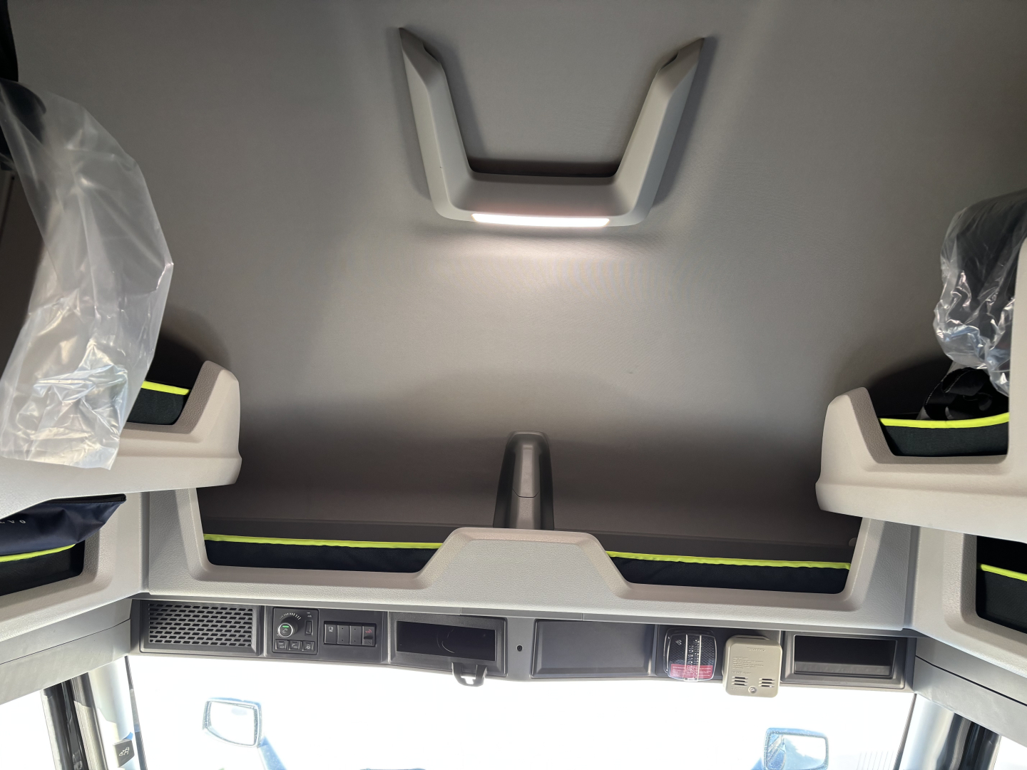 Volvo VNL64T860 sleeper cab interior showing overhead storage and dashboard controls with light reflections.