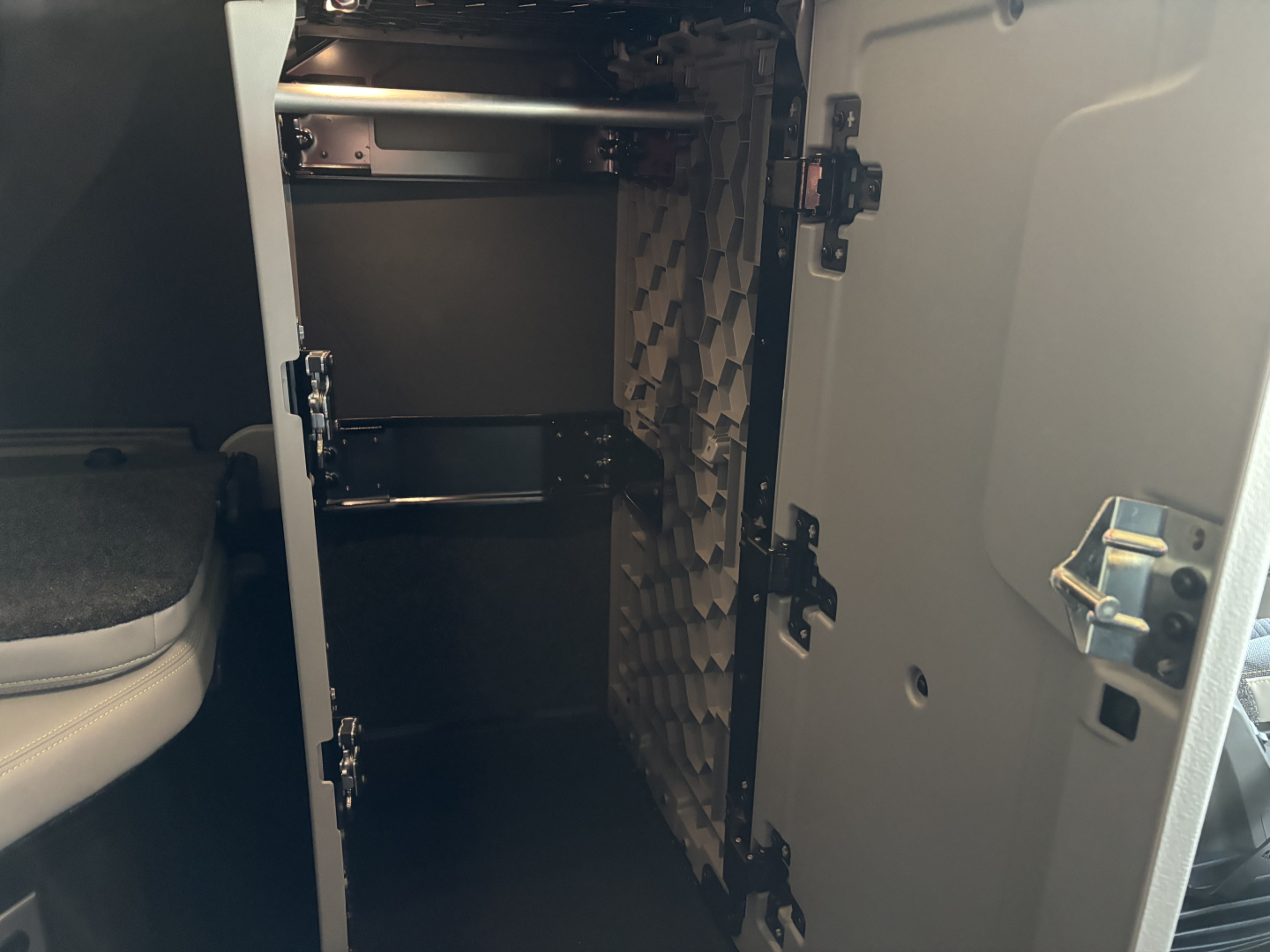 Volvo VNL64T860 sleeper cab storage compartments open showing shelves and partitioned interior with foam padding on wall.