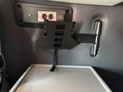 Volvo VNL64T860 cab interior showing mounting bracket and small screen, 12V power outlet panel, and a horizontal metallic tray.