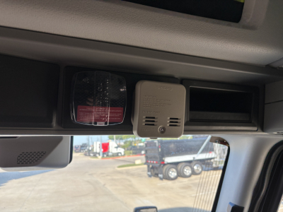 Truck cab interior overhead area with a small grey device and two black housings visible
