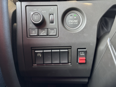 Volvo VNL64T860 dash area showing engine start-stop button and switch panel with circular ignition, various controls, and a red hazard/emergency switch.
