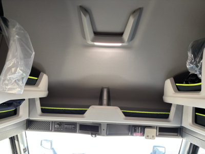 Volvo VNL64T860 sleeper cab interior showing overhead storage and dashboard controls with light reflections.