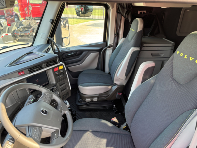 Cab interior of a new Volvo VNL64T860 semi-truck showing steering wheel, driver seat, passenger seat, and dashboard with control panels.