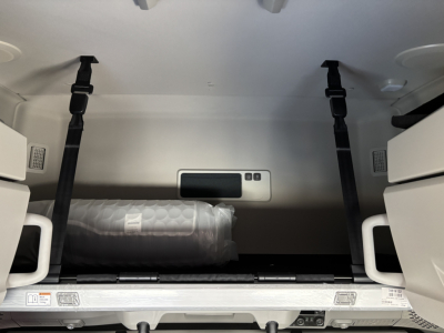 Truck cargo space of a new Volvo VNL64T860 sleeper showing storage area with strap anchors and a plastic-wrapped item.