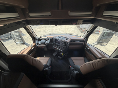 Cab interior of a new Mack PR64T76H truck showing dashboard, steering wheel, and front seats with brown upholstery.