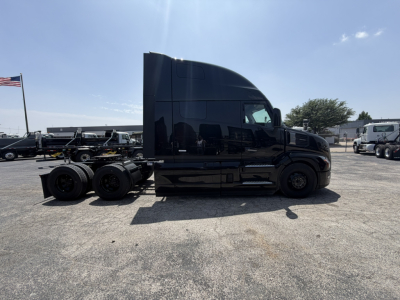 Truck side view of a black Mack PR64T76H tractor with high-roof sleeper, showing rear axles and wheels, cab silhouette, and trailer hitch area.