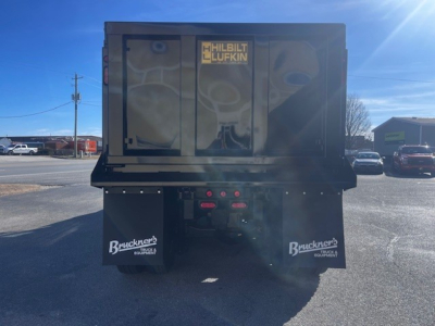 Dump truck bed showing Brackeners/Business logo mudflaps and Hilbilt Lufkin storage doors on a black dump body with rear access.