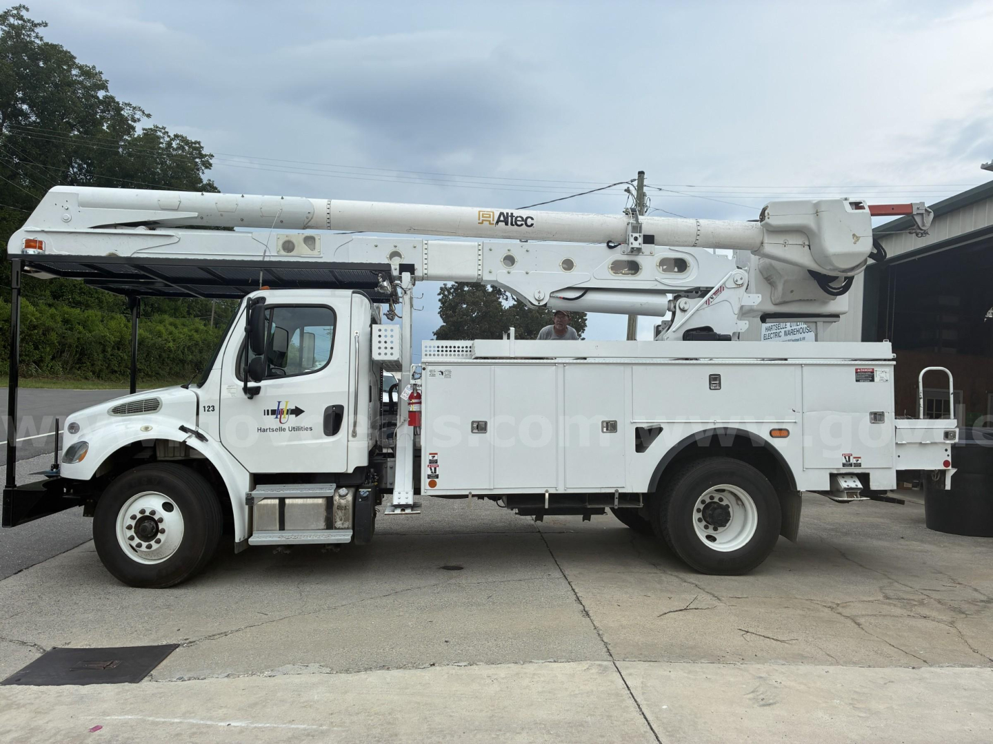 Bucket truck on concrete lot, white Freightliner M2 106 utility body with extendable boom labeled 'Alltecc' and service compartments, VIN 3ALACYFC1JDJN4113.