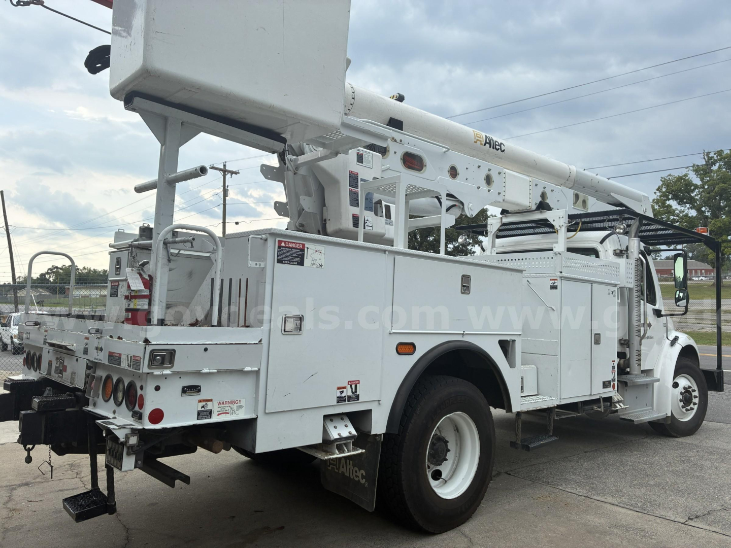 Truck body of a used 2018 Freightliner M2 106 bucket truck showing utility compartments and hydraulic boom from rear quarter view.