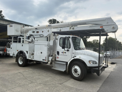 Bucket truck on service lot showing extended boom and mid-mounted controls, white Freightliner M2 106 bucket crane