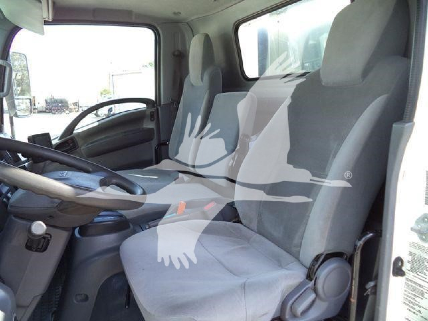Isuzu NPR-HD truck cab interior showing driver seat and passenger seat, steering wheel, and dashboard view.