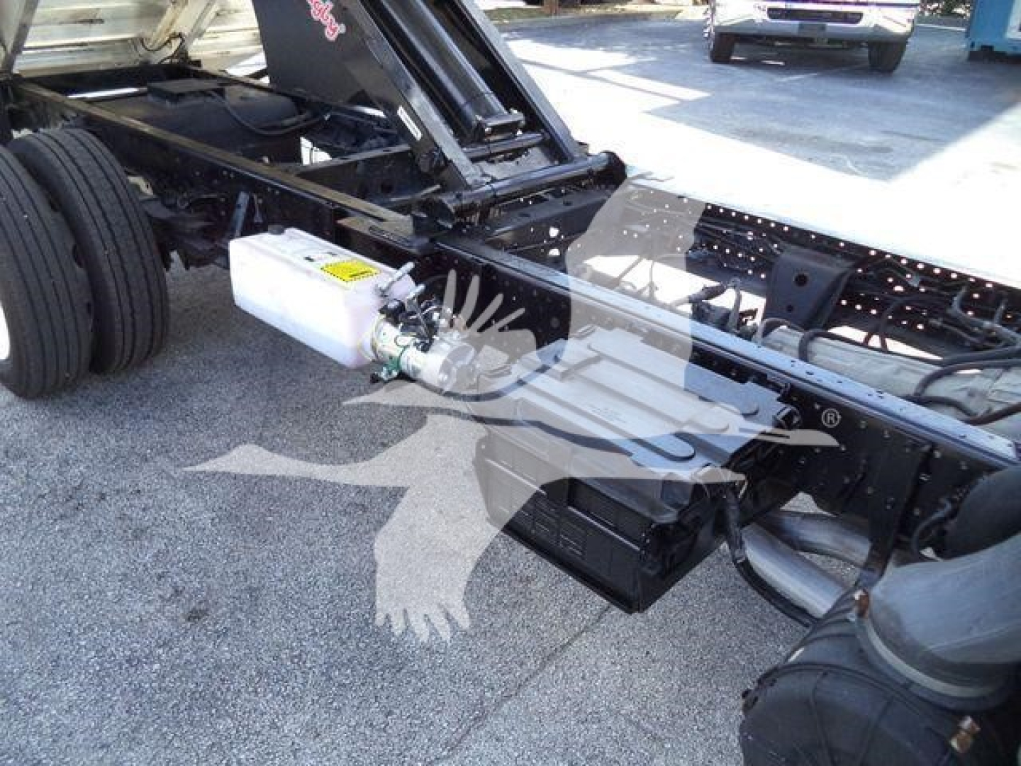 Isuzu NPR-HD truck chassis showing white reservoir and hydraulic lines near frame rail and front axle.