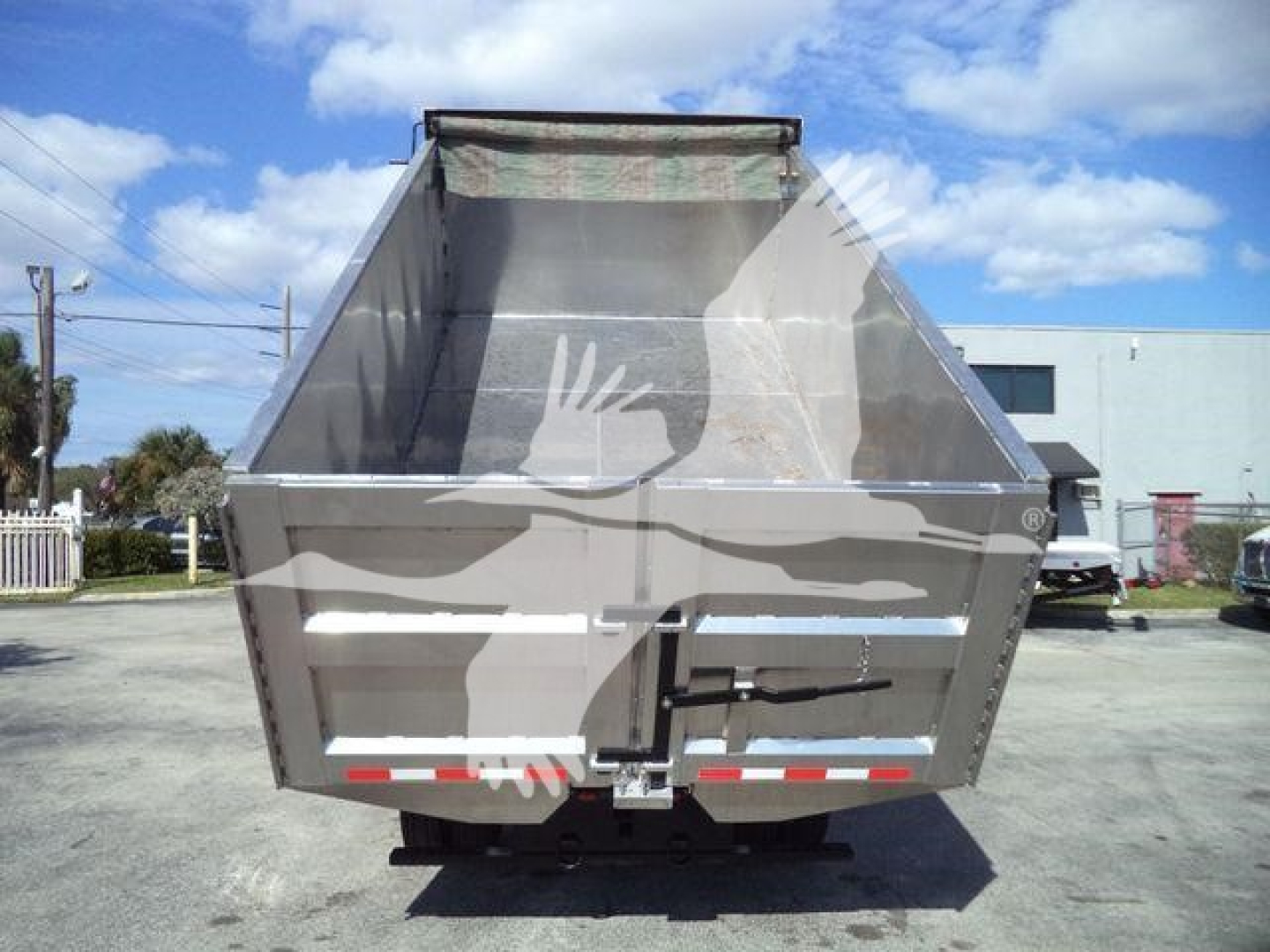 Dump bed of Isuzu NPR HD truck seen from rear, empty cargo area, tailgate and reflective red/white safety stripes.