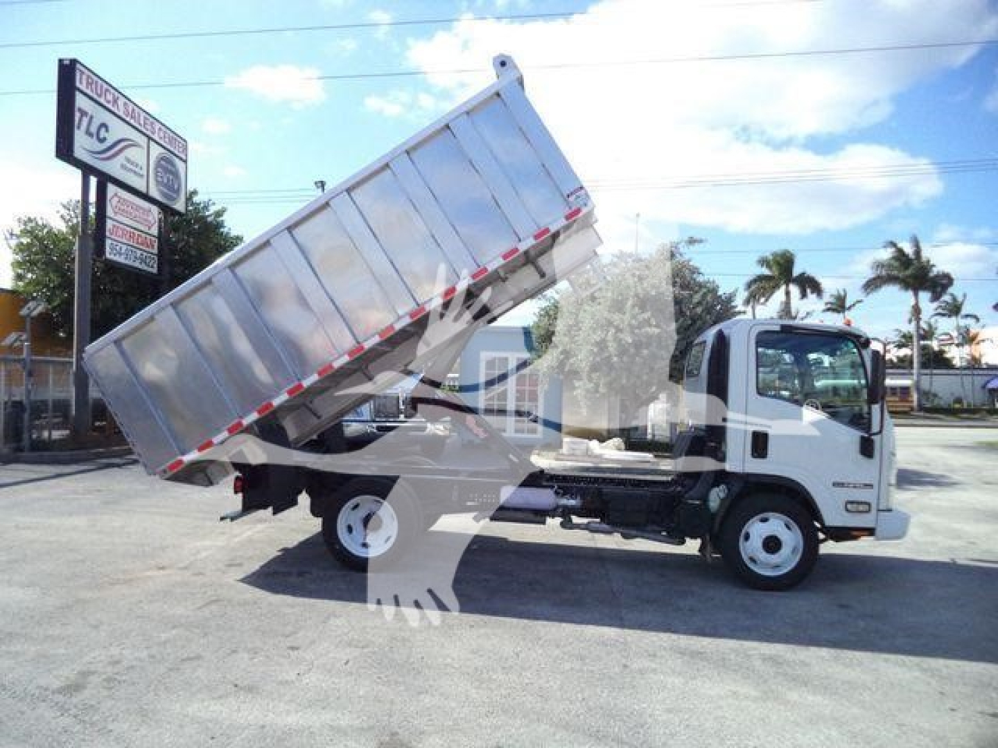 Isuzu NPR-HD dump truck in service position with bed raised, side view showing cab and dump bed.