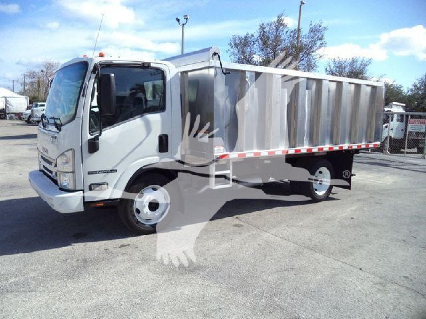 Isuzu NPR HD dump truck side view showing white cab and gray dump bed with red and white reflective striping along the side.