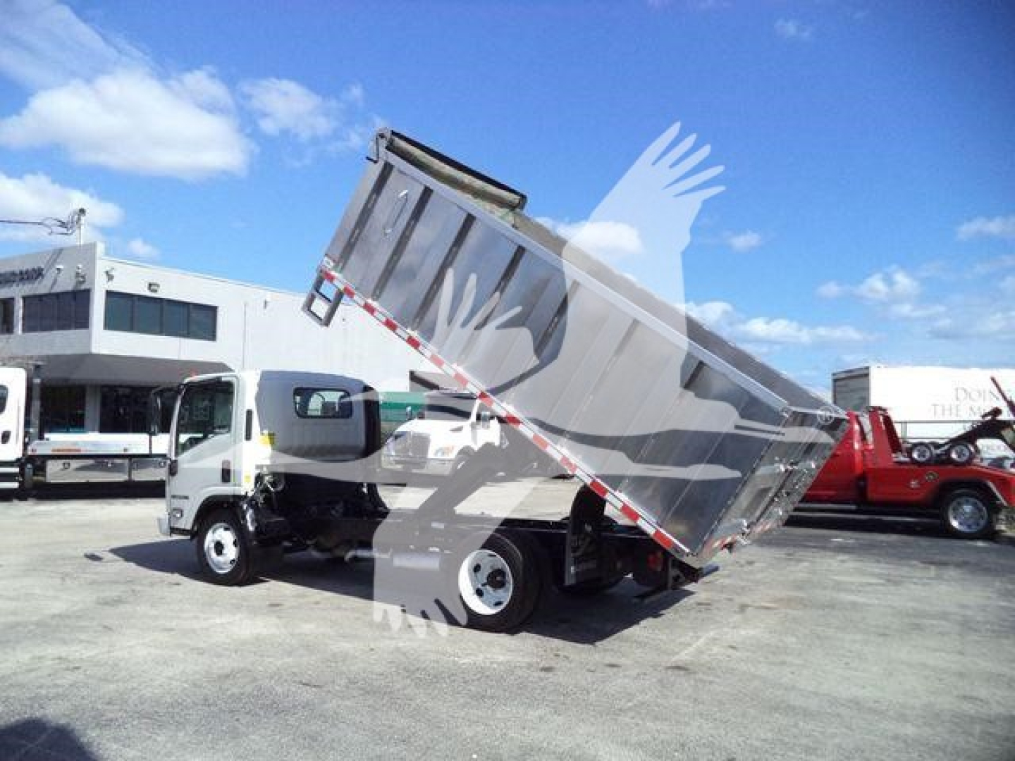 Isuzu NPR-HD dump truck in a tipping position showing the cargo bed raised.