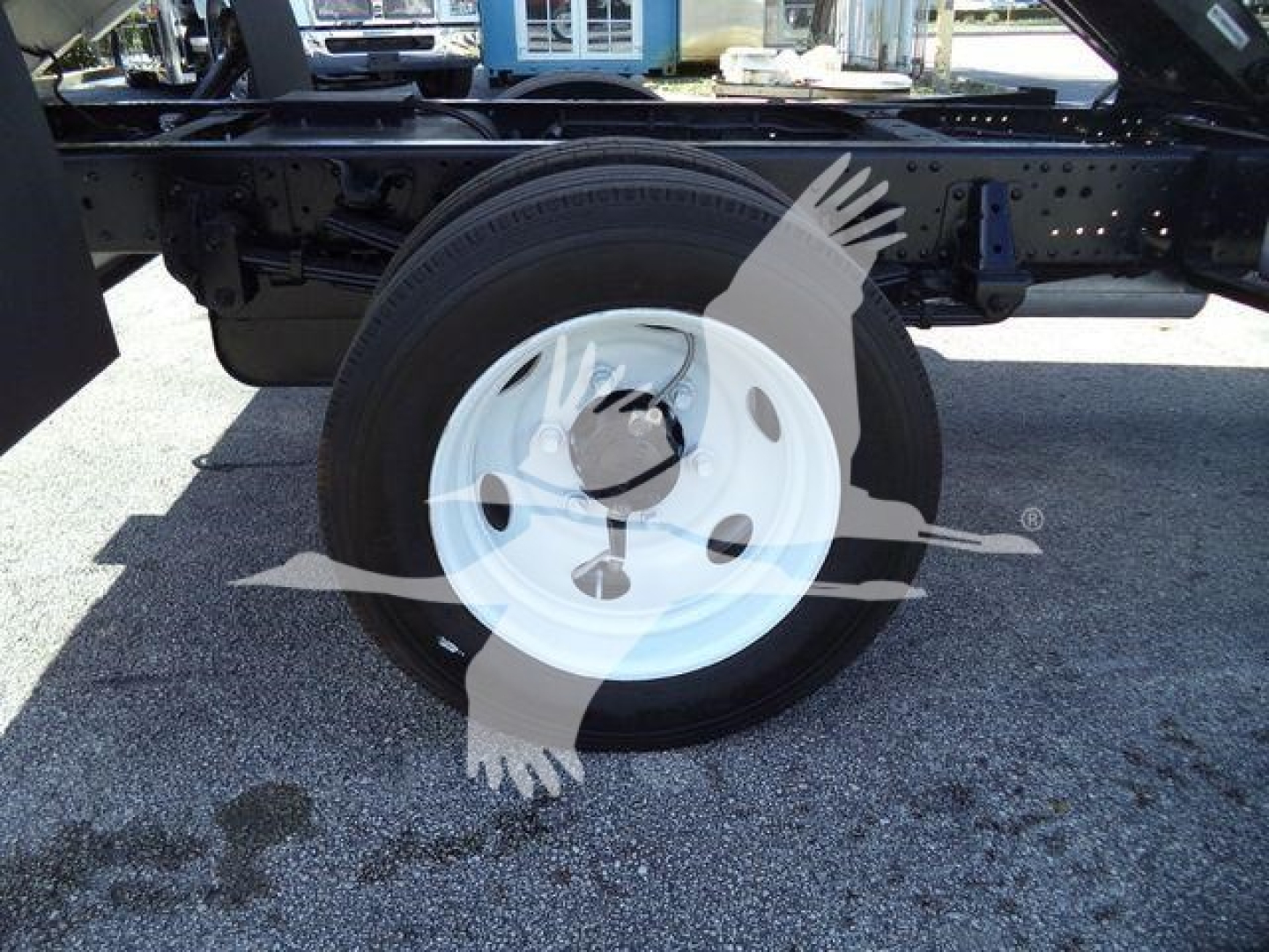Wheel and chassis side view of a 2017 Isuzu NPR HD truck showing a white steel wheel with black tire and surrounding frame components.