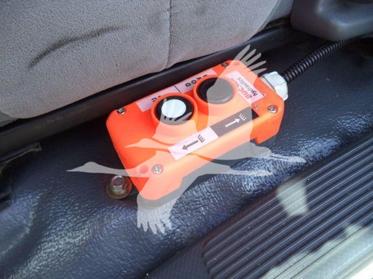 Isuzu NPR-HD truck interior showing an orange momentary control box with directional arrows and labeled switches.