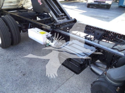 Isuzu NPR-HD truck chassis showing white reservoir and hydraulic lines near frame rail and front axle.
