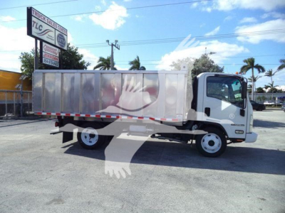 Isuzu NPR-HD dump truck in a dealership lot, side view, cargo bed, white cab, chrome wheels, TCL dealership sign in background.