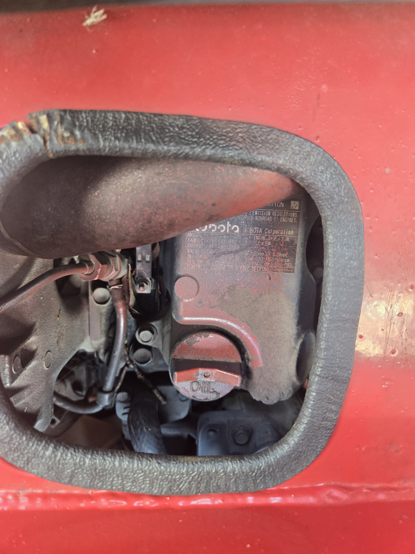 Engine bay access showing some hydraulic components and labels on a red lift vehicle side